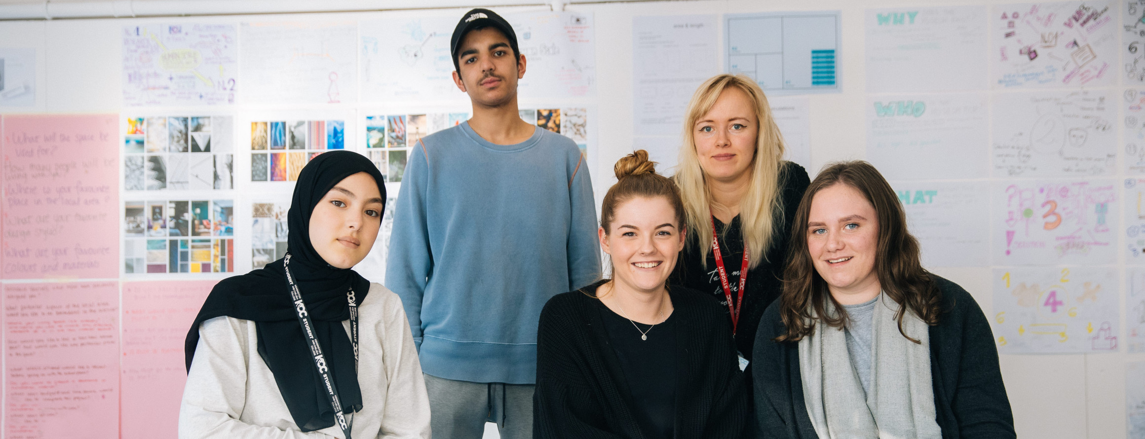 A photograph showing a group of teenagers and tutor, in a classroom environment