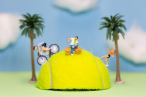 Macrophotography of cyclists cycling over half a tennis ball
