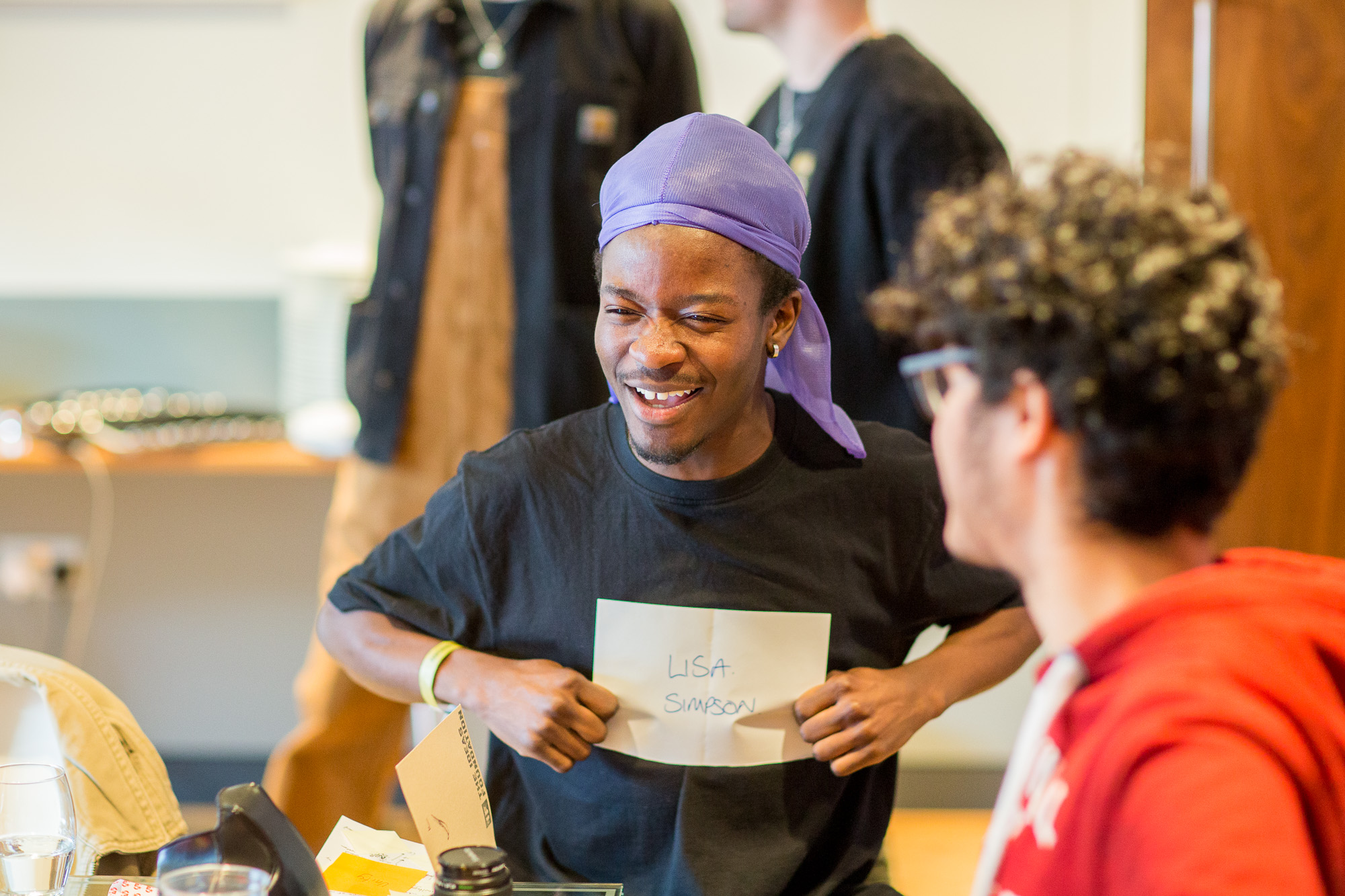 Student smiling and holding up paper as peer looks on and play more